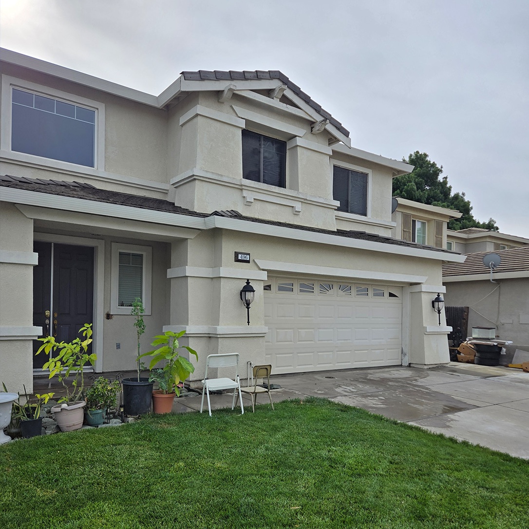 Two-story home before, with worn beige stucco